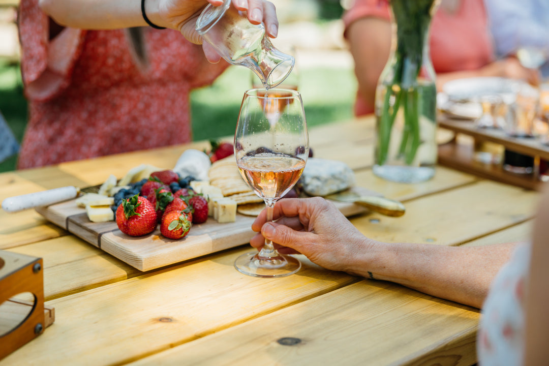 pouring wine sample in a glass with a charcuterie board in background
